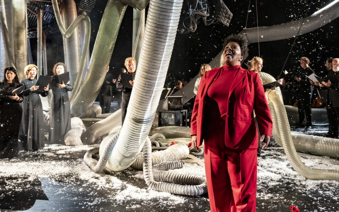 opera stage with striking abstract set and a Black woman in a red suit in the middle of it, performing