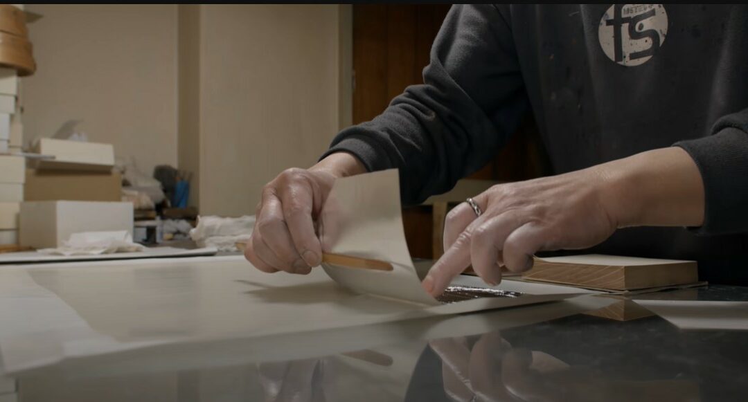 a person's hands working on making fabric from silver foil