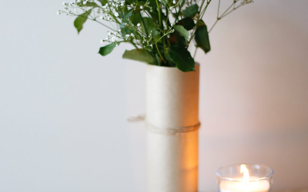 a beautiful table set in neutral colors with a candle, a plate of butter, and a small bouquet in a tall vase