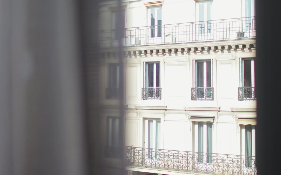 exterior of an old European-looking apartment building with tall windows and white exterior