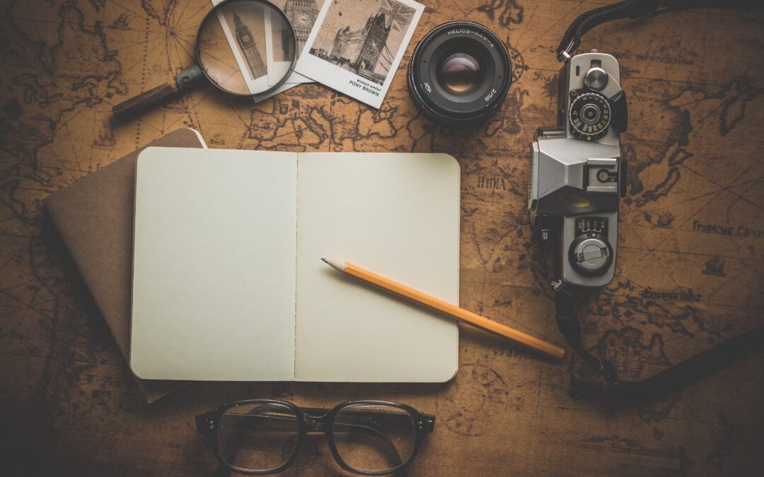 map, notebook, pencil, camera, photos, magnifying glass, artfully in a flatlay