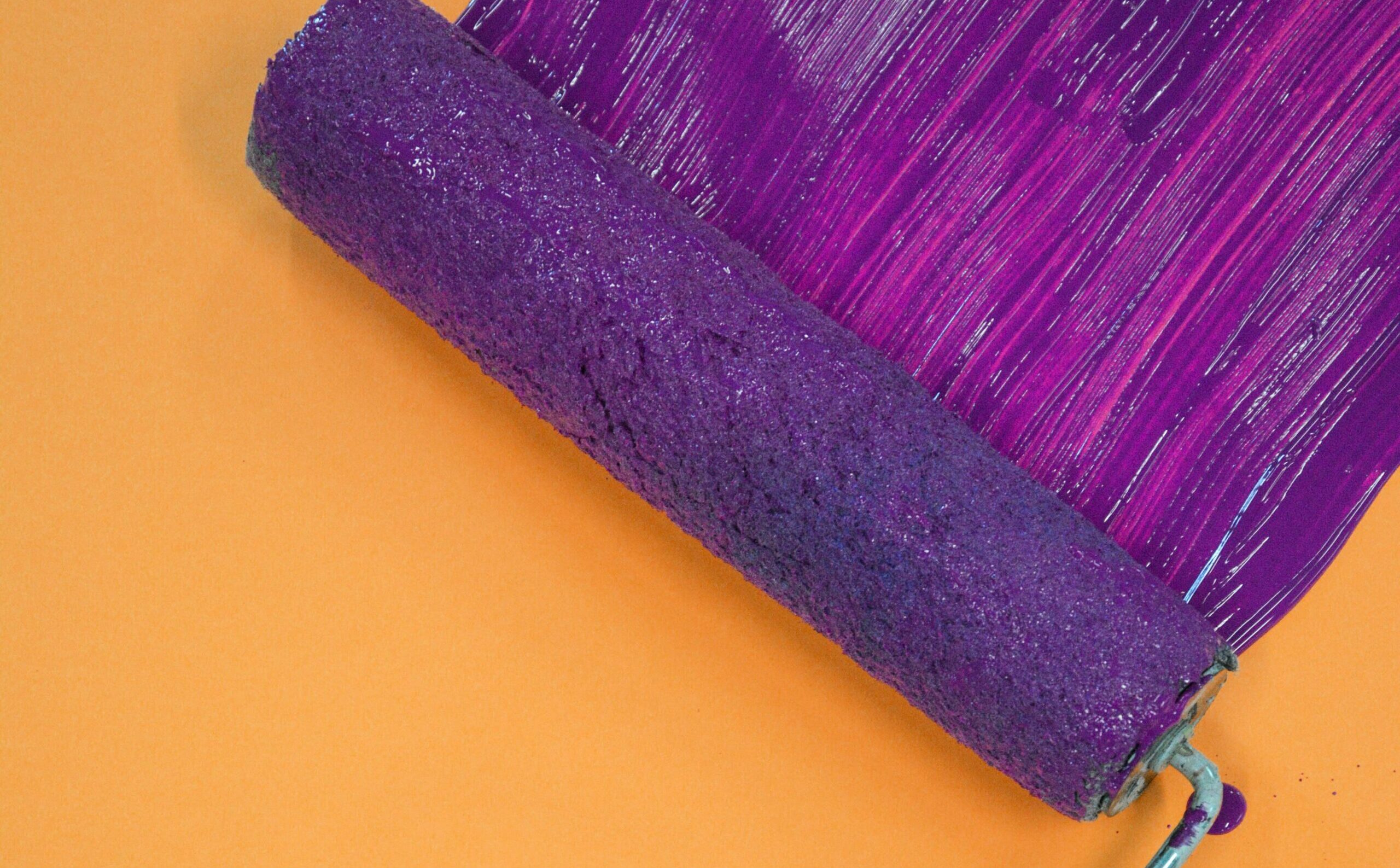 pexels-cassidy-muir-1079619-2065971 orange wall with a purple roller of paint swiping across it