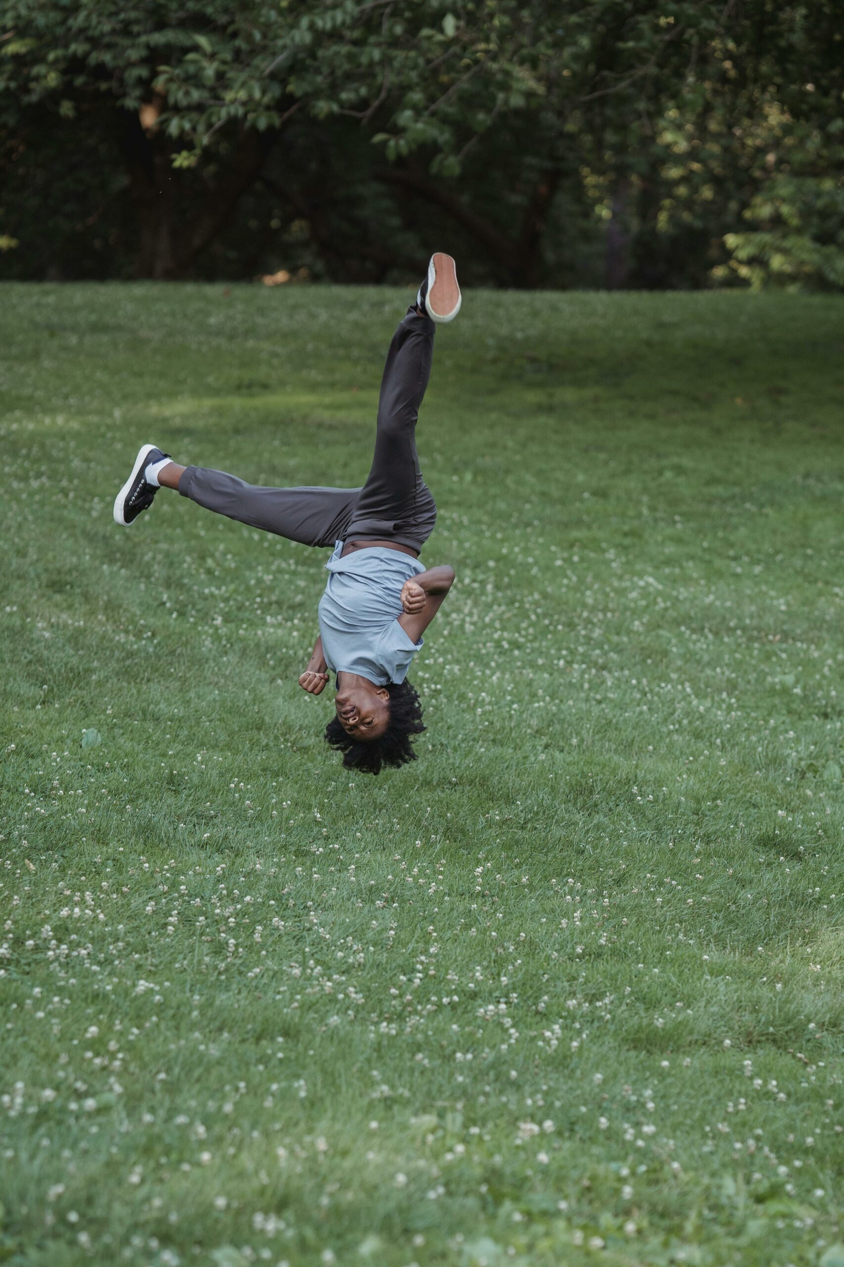 pexels-mizunokozuki-12887201 a black human with a medium afro turning a no-hands cartwheel in a park